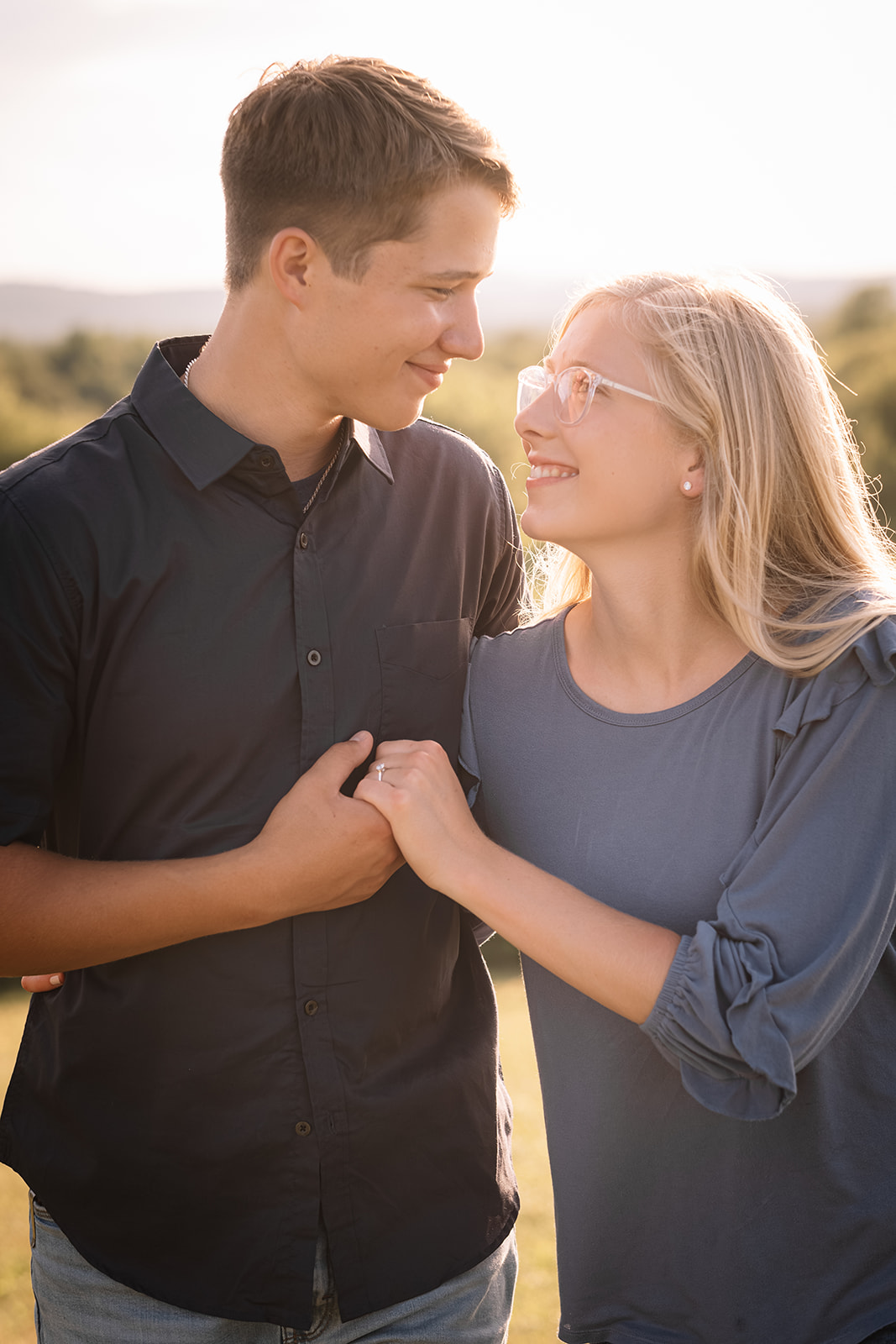 Sophie and William looking at each other in warm golden-hour light, mountains softly visible in the background